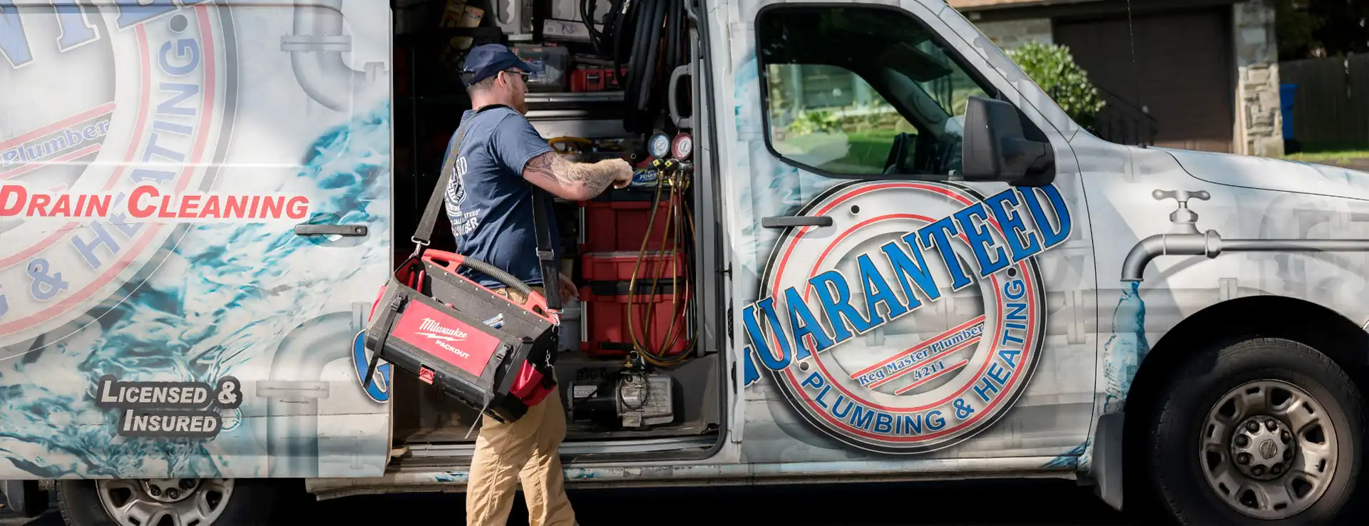 a workger pulling tools out of a Guaranteed Plumbing van